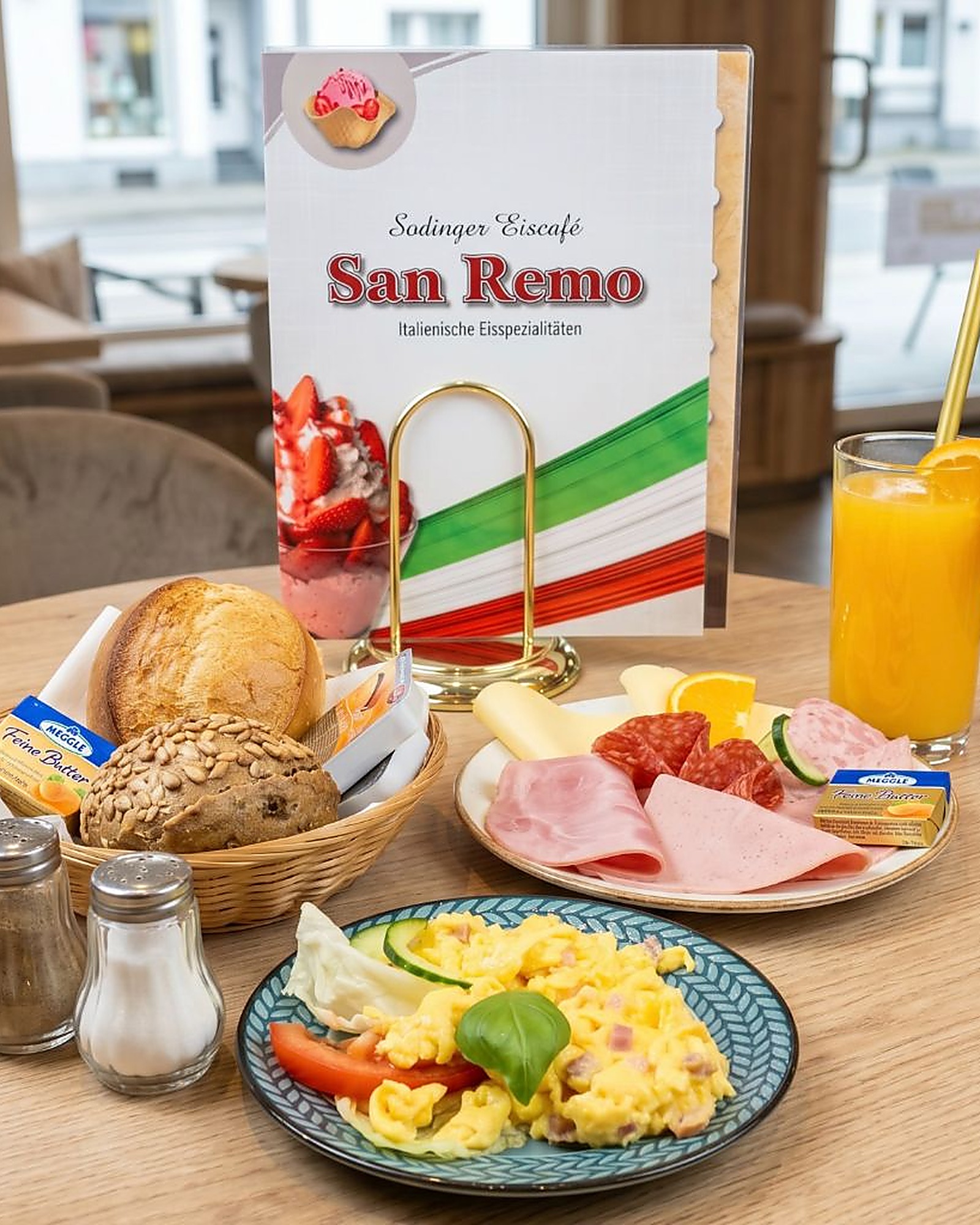 Frühstücksteller mit Orangensaft und Brotkorb im Eiscafé San Remo